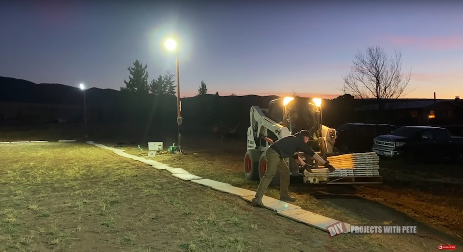 Laying out the Nice Rink hockey boards on a pallet with a skid steer